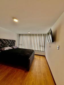 une chambre avec un grand lit noir et une fenêtre dans l'établissement aparta estudio de lujo, à Pasto