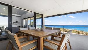 a dining room with a table and chairs and the ocean at Puesta de Sol Home by Wine Coast Holiday Rentals in Sellicks Beach