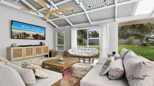 a living room with white furniture and a flat screen tv at Sea Gypsy by Wine Coast Holiday Rentals in Aldinga Beach