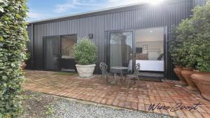 WillungaHideaway Nook by Wine Coast Holiday Rentals的大楼前的天井配有2把椅子和1张桌子