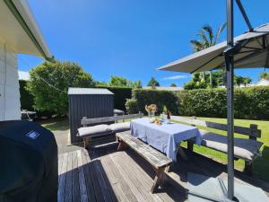 a table and bench on a deck with an umbrella at Cosy Hahei Retreat in Hahei