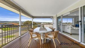 a dining room with a table and chairs on a balcony at R & R Aldinga Beach by Wine Coast Holidays in Aldinga Beach