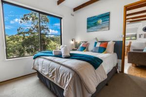 a bedroom with a bed and a large window at Jetty View - Lorikeet Cabin in Nungurner