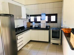 eine Küche mit weißen Schränken und schwarzen Arbeitsplatten in der Unterkunft Casa-Z pertinho do mar in Barra de São Miguel + 4 Fotos