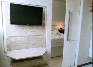 a tv on a wall in a bedroom with a bed at Flats Lago Norte MOTO CAPITAL 3 PESSOAS! in Brasilia