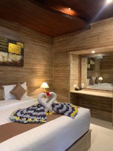 a bedroom with a bed with swans towels and a mirror at Jenggala Hill in Nusa Lembongan