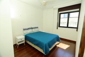 Un dormitorio con una cama azul y una ventana. en Conforto e localização privilegiada na Pituba, en Salvador 23 fotos más