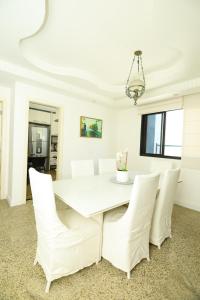 un comedor blanco con una mesa blanca y sillas blancas en Conforto e localização privilegiada na Pituba, en Salvador