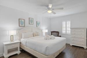a bedroom with a white bed with two teddy bears on it at South Seas Bayside Villa 4116 - Newly Renovated Marina View Condo in Captiva +11 photos