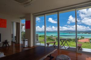 a living room with a table and a view of the ocean at 20C Ryukyu in Nakijin