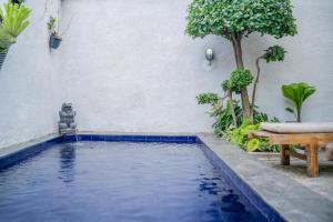 una piscina di fronte a un muro bianco con un tavolo di Twin OLA a Tabanan