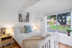 a white bedroom with a bed and a large window at The Beach Box in Manyana +21 photos