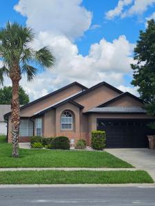 a house with a palm tree and a garage at Minnie Heaven in Kissimmee