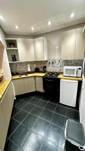 a kitchen with white cabinets and a stove and a microwave at Flat Cosmopolitan Praia no Gonzaga com Varanda - Estacionamento Incluso in Santos
