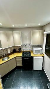 a small kitchen with a stove and a microwave at Flat Cosmopolitan Praia no Gonzaga com Varanda - Estacionamento Incluso in Santos
