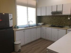 a kitchen with white cabinets and a sink and a window at Calma Villa Jalan Sultanah in Alor Setar +4 photos