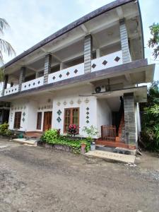 Una gran casa blanca con un porche delantero y escaleras. en Lamancha Homestay, en Kuta Lombok