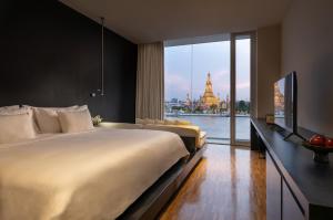 a bedroom with a large bed and a view of a building at Sala Rattanakosin Bangkok in Bangkok