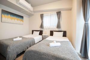 twee eenpersoonsbedden in een kamer met een raam bij Regale Dotonbori East in Osaka