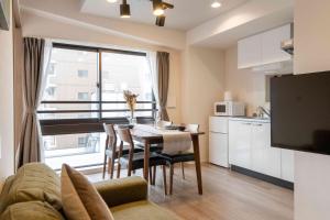 een woonkamer met een tafel en een keuken bij Regale Dotonbori East in Osaka