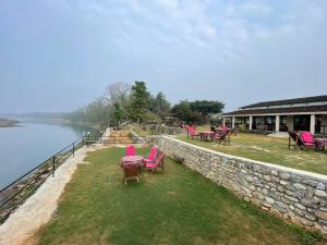 索拉哈Chitwan Riverside Resort的一组椅子坐在水边的墙上