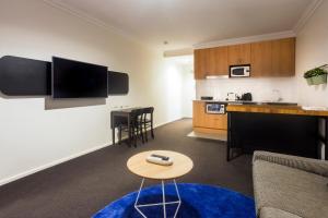パースにあるCosy & Central Studio APT in The Heart of Perthのソファとテーブルとキッチンのあるリビングルーム