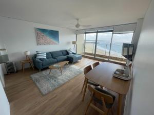sala de estar con sofá azul y mesa con sillas en Oceanic 28 On The Beach, en Forster