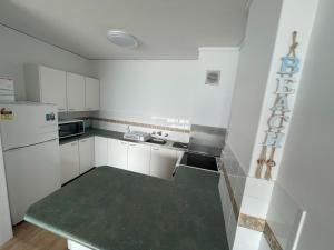Una pequeña cocina con gabinetes blancos y un refrigerador. en Oceanic 28 On The Beach, en Forster 10 fotos más