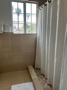 a bathroom with a shower curtain and a window at Plaza Hotel Gardena in Gardena