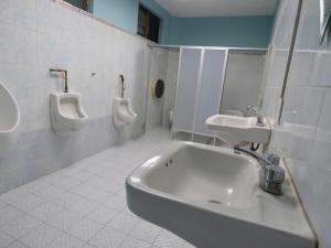 a bathroom with three urinals and a sink and toilets at Hostal Centro Histórico in Oaxaca City