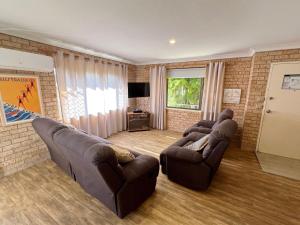 Sala de estar con 2 sofás de cuero y TV en Beach Shack SWR - Bring your own linen, en South West Rocks