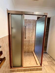una ducha con puerta de cristal en un baño en Beach Shack SWR - Bring your own linen, en South West Rocks 3 fotos más