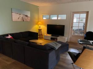 a living room with a couch and a flat screen tv at Højmosegård værelse 1 in Varde