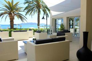 a lobby with chairs and palm trees and the ocean at BG Nautico Ebeso in Ibiza Town