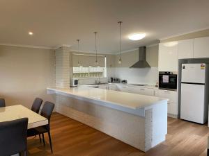 a white kitchen with a large island in the middle at Waterside Mulwala in Mulwala