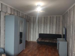 a living room with a couch and wooden floors at Однокомнатная квартира недалеко от озера Балхаш in Balqash