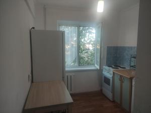 a kitchen with a white refrigerator and a window at Однокомнатная квартира недалеко от озера Балхаш in Balqash