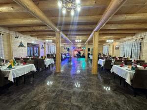 a dining room with tables and chairs and a chandelier at Pensiunea Vânătorul in Dămuc