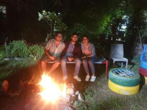 a group of three people sitting around a fire at Dream Vision Guest House in Diu