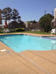 a swimming pool with blue water and two chairs at MacThrift Motor Inn in Virginia Beach