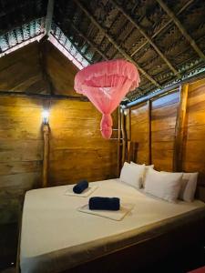 a bed in a room with a pink umbrella at LakeSide Cabana Tissamaharama in Tissamaharama