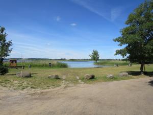 a park with rocks and a tree and a lake at Strandhaus am Oberuckersee in Warnitz +11 photos