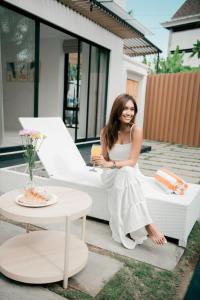 a woman in a white dress sitting on a couch at Seminyak vila luxury 4Br near beach LAfavela in Seminyak