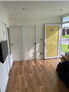 a living room with a large yellow door and wooden floors at Little Spain in Selsey