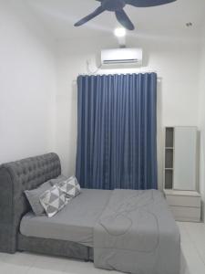 a bedroom with a bed with a blue curtain and a ceiling fan at Amara Homestay Kuantan Airport in Kuantan