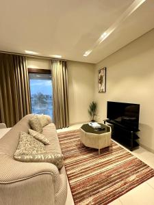 a living room with a couch and a television at 2 Hawana VIP Studio in Ma‘mūrah