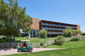 a person riding a golf cart in front of a building at Empordà Golf Resort in Torroella de Montgrí