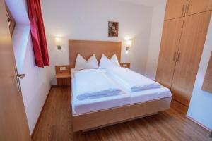 アーヘンキルヒにあるFerienwohnung Achenseeのウッドフロアのベッドルーム1室(白いシーツ付きのベッド1台付) +14枚の写真