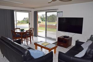 Una sala de estar con un sofá, un televisor y una mesa. en Pacific Court 1 - Bring your own linen., en South West Rocks