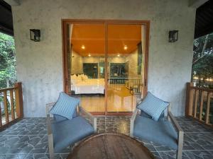 eine Terrasse mit zwei Stühlen und einem Tisch auf einer Veranda in der Unterkunft BaHo Eco Beat in Ninh Hòa